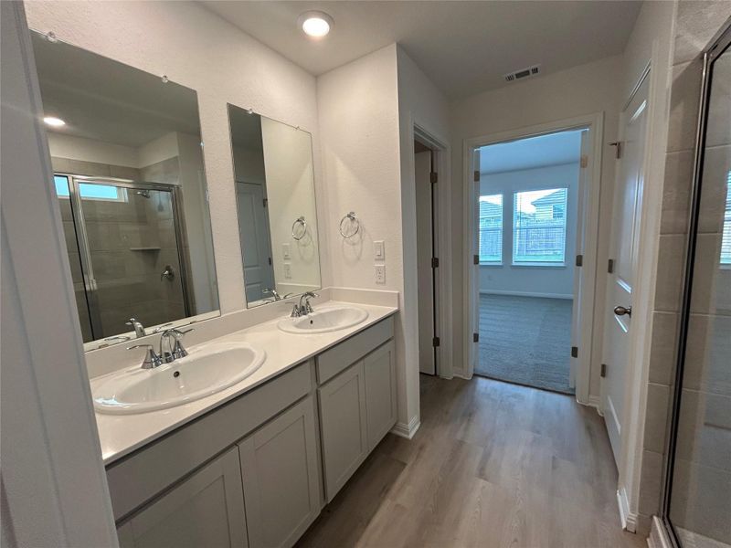 Full bath featuring a stall shower, double vanity, and light wood-type flooring Full bath featuring a stall shower, double vanity, and light wood-type flooring