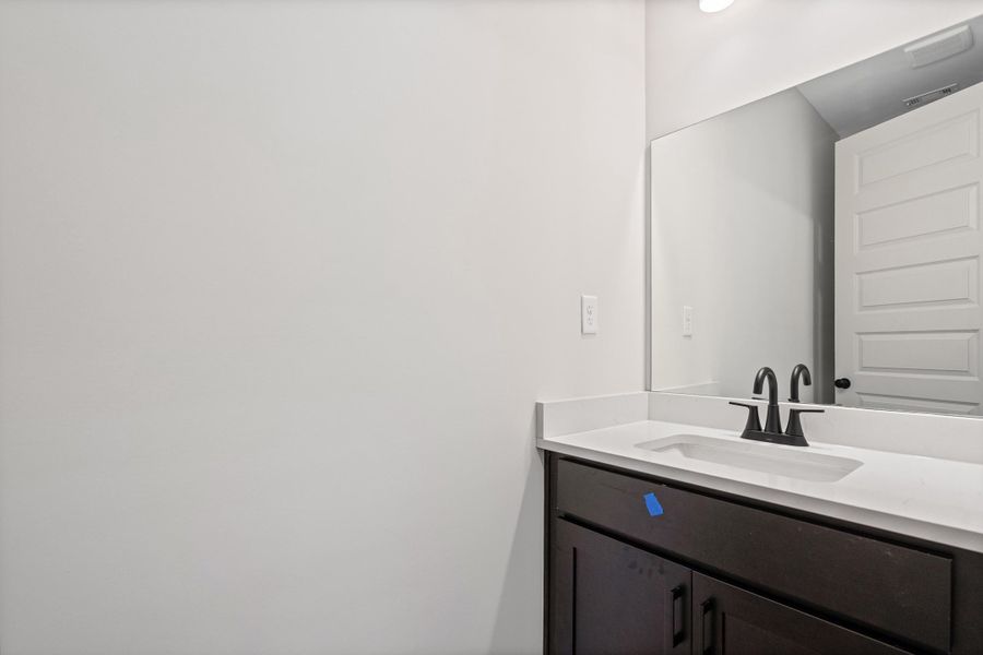 Dark wood-finish vanity with a white countertop and integrated sink Dark wood-finish vanity with a white countertop and integrated sink