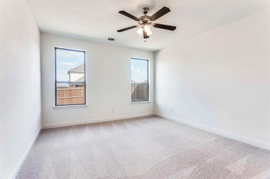 Carpeted empty room featuring baseboards and a ceiling fan