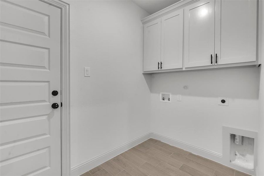 Laundry area with hookup for an electric dryer, cabinet space, hookup for a washing machine, gas dryer hookup, and light wood-style flooring Laundry area with hookup for an electric dryer, cabinet space, hookup for a washing machine, gas dryer hookup, and light wood-style flooring