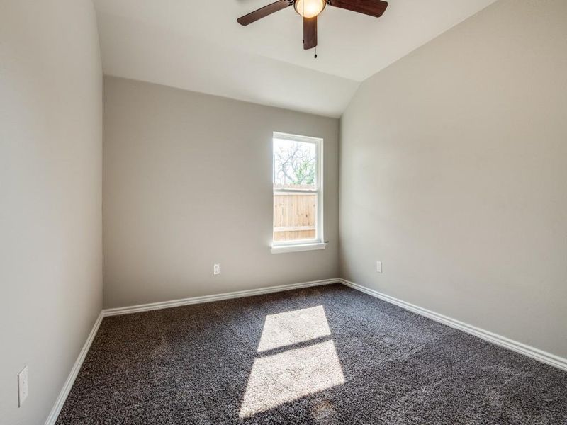 Spare room with dark carpet, baseboards, a ceiling fan, and vaulted ceiling Spare room with dark carpet, baseboards, a ceiling fan, and vaulted ceiling
