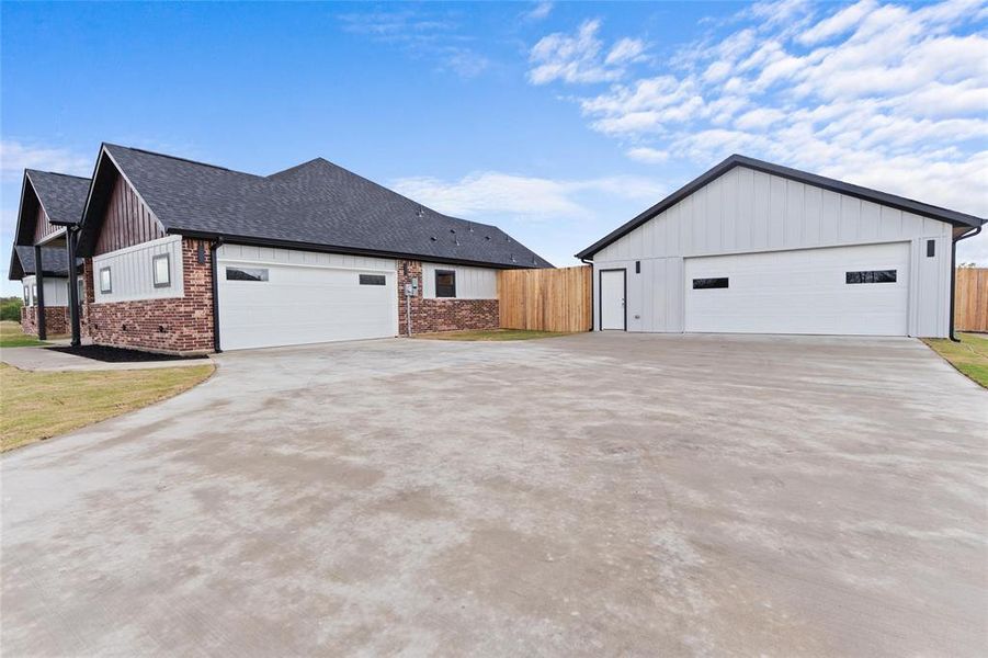 View of home's exterior featuring a detached garage, brick siding, roof with shingles, and board and batten siding