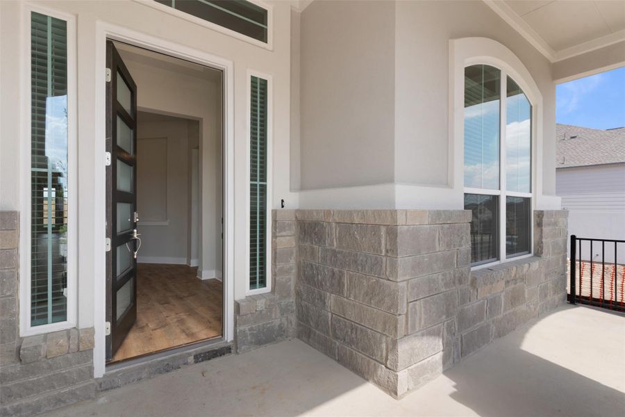 Property entrance featuring stone siding, stucco siding, and a patio area