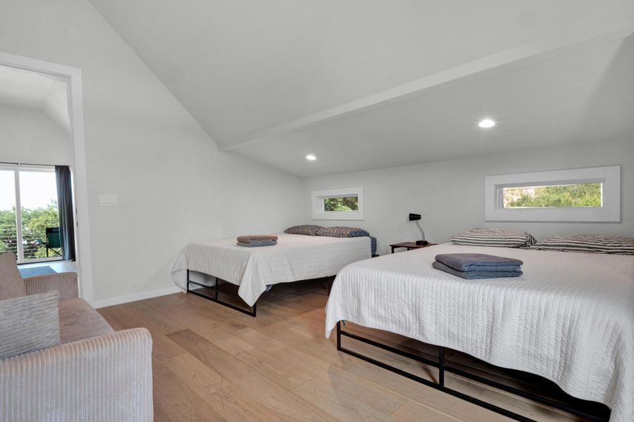 Bedroom featuring vaulted ceiling, light wood-type flooring, multiple windows, and recessed lighting