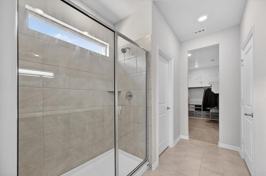 Bathroom featuring a spacious closet, a stall shower, and light tile patterned floors