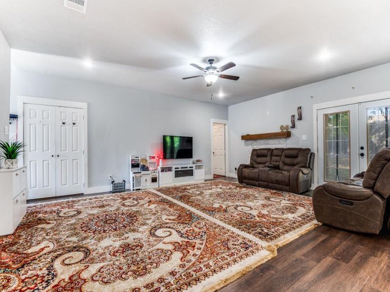 Living room with french doors, dark wood-style floors, and a ceiling fan Living room with french doors, dark wood-style floors, and a ceiling fan
