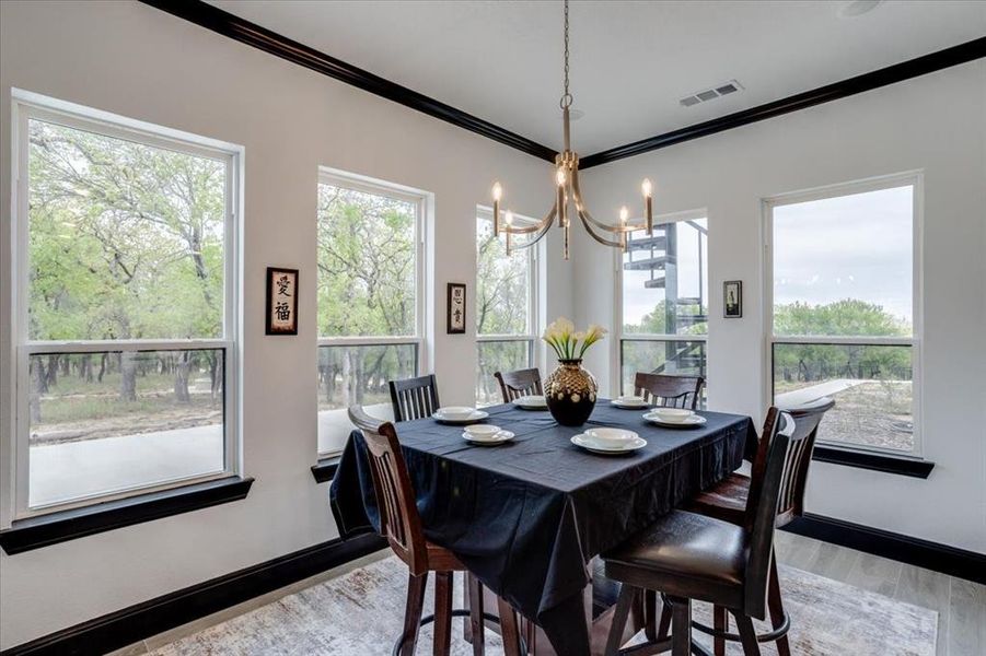 Dining room with light tile flooring, crown molding, and suspended lighting