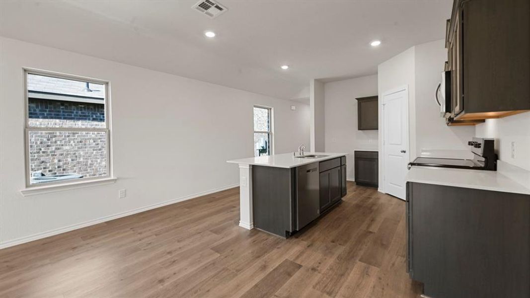 Kitchen featuring stainless steel appliances, a kitchen island with sink, recessed lighting, dark wood finished floors, and dark wood finish cabinets