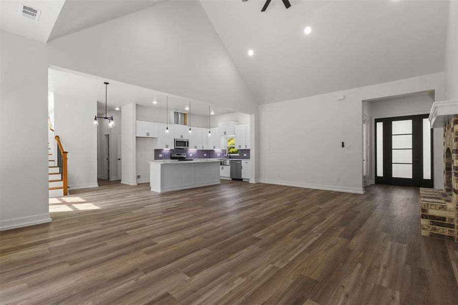 This spacious interior features high vaulted ceilings, recessed lighting, and wood-look flooring throughout