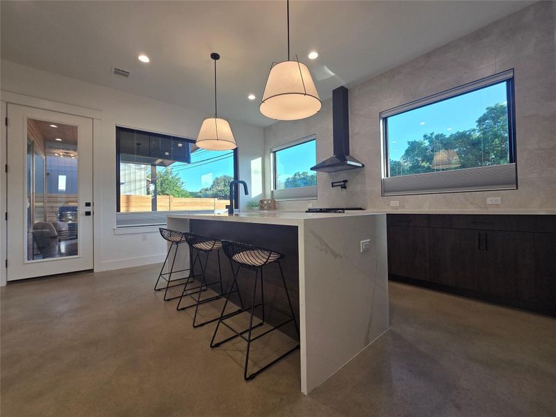 Polished concrete floors and a waterfall kitchen island create a sleek contemporary space.