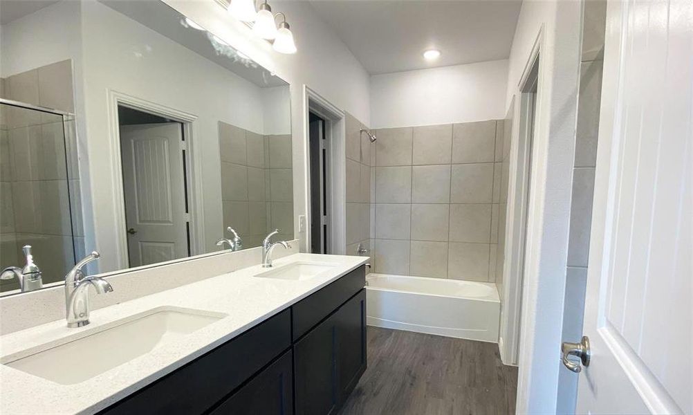 Bathroom with hardwood / wood-style flooring, vanity, and tiled shower / bath