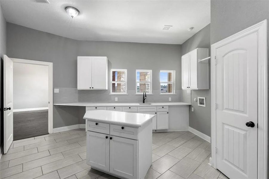 Kitchen featuring light countertops, white cabinets, a center island, and decorative backsplash