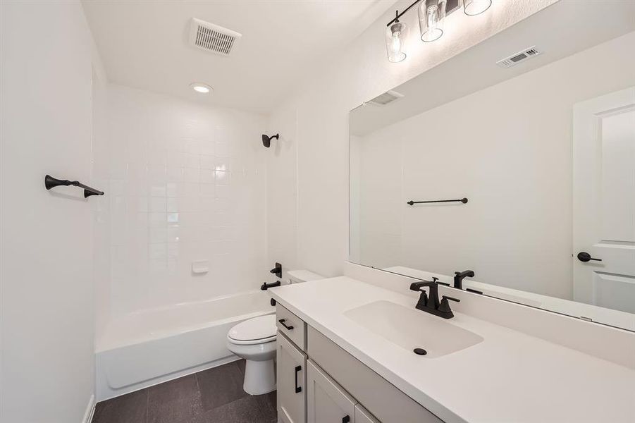 Full bathroom featuring tiled shower / bath, vanity, and toilet