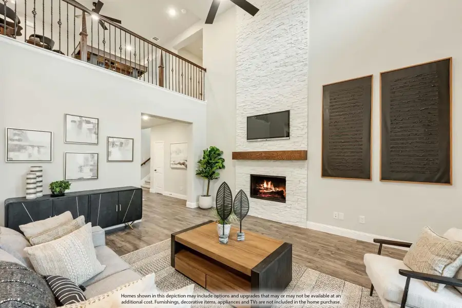 Two-story living room with white stone fireplace, wood floors, and open loft railing above