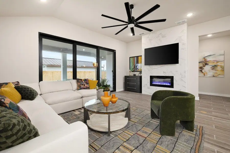 An inviting gathering space features an elegant fireplace, high ceilings, and large sliding glass doors.