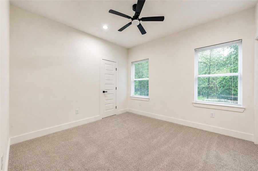 Bright and inviting 4th bedroom featuring plush carpeting, modern ceiling fan, and ample natural light from dual windows, perfect for relaxation or a cozy retreat.