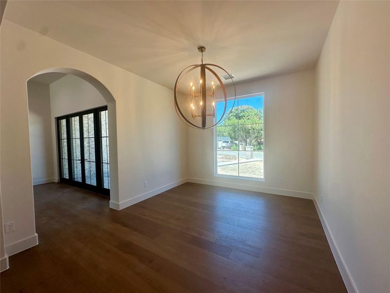 Rich hardwood floors and an arched doorway bring timeless elegance to this light-filled room.