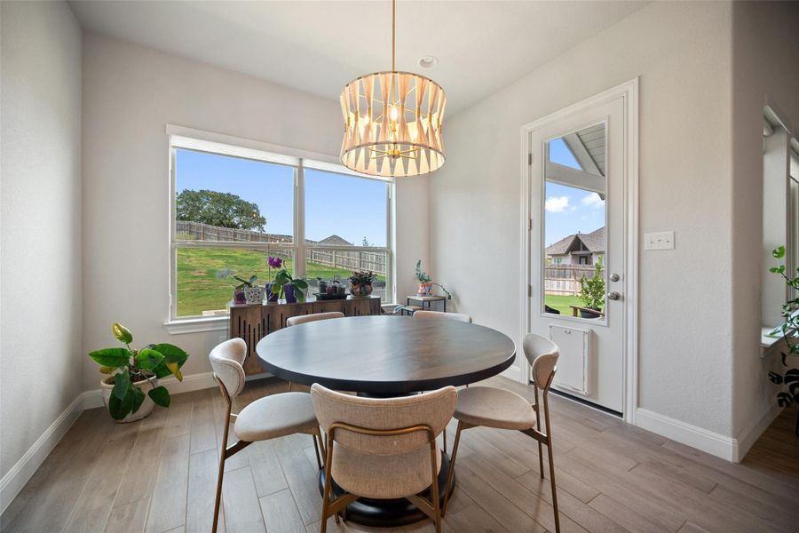 Dining area featuring healthy amount of natural light, light wood-style floors, and a chandelier