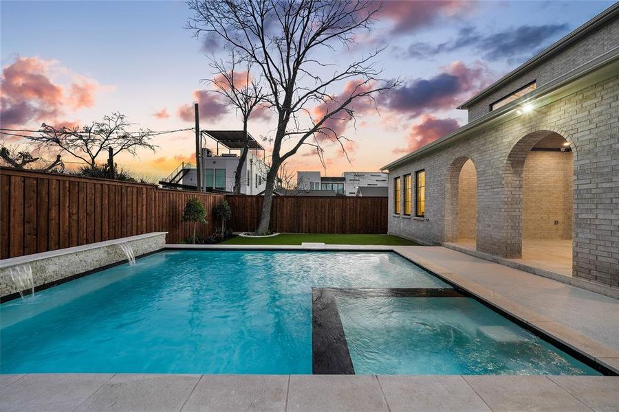 Combined pool / hot tub with a fenced backyard and a patio area Combined pool / hot tub with a fenced backyard and a patio area