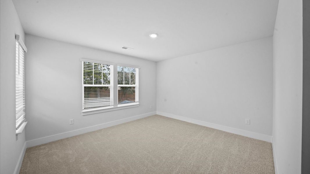 Highly functional bedroom with large windows, carpeted flooring, and tasteful finishes throughout Highly functional bedroom with large windows, carpeted flooring, and tasteful finishes throughout