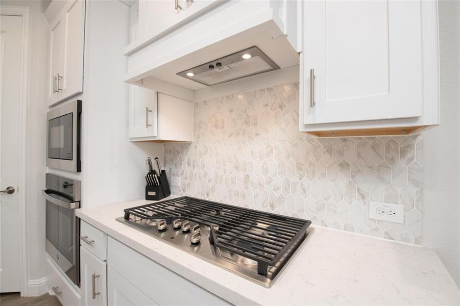 Prepare meals with ease using stainless steel appliances, a gas cooktop, custom vent hood, and designer tile backsplash that adds both style and function. Prepare meals with ease using stainless steel appliances, a gas cooktop, custom vent hood, and designer tile backsplash that adds both style and function.