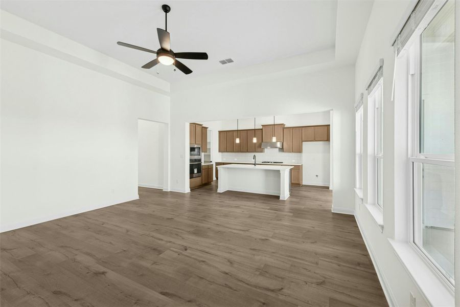Unfurnished living room with dark wood-style floors, a ceiling fan, and a high ceiling