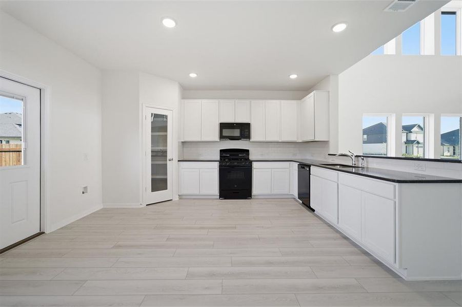 Contemporary kitchen featuring white cabinetry, black countertops, and a full suite of black appliances