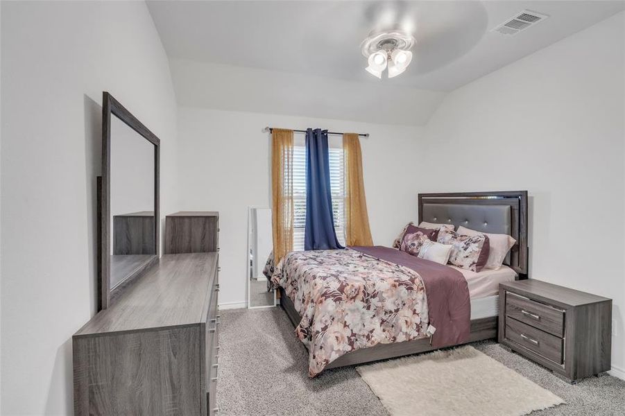 Carpeted bedroom featuring vaulted ceiling and ceiling fan