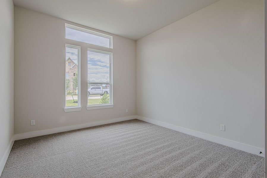Versatile front-facing bedroom with large picture windows and elevated transom for added natural light and curbside views.