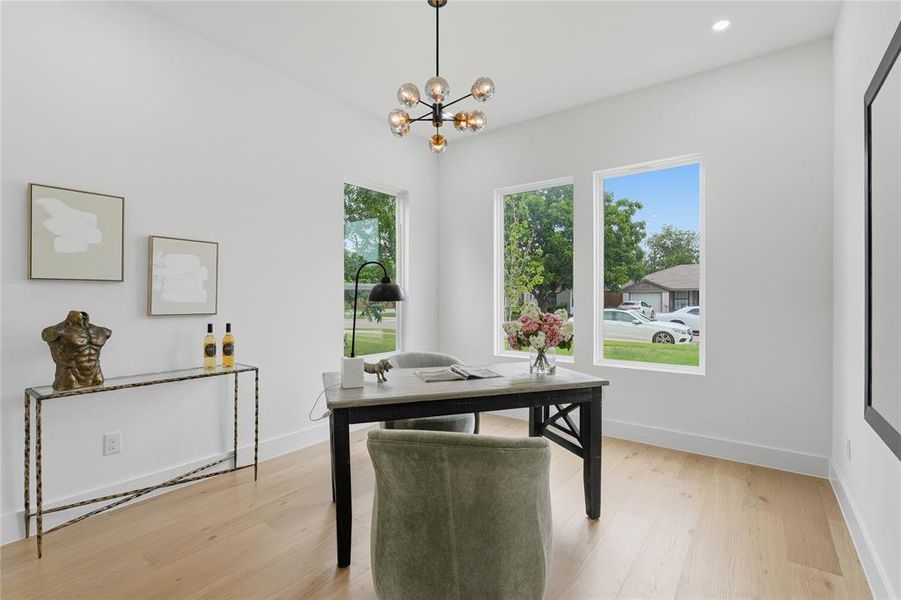Bright room featuring light wood-finish flooring, white walls, and three vertical windows Bright room featuring light wood-finish flooring, white walls, and three vertical windows