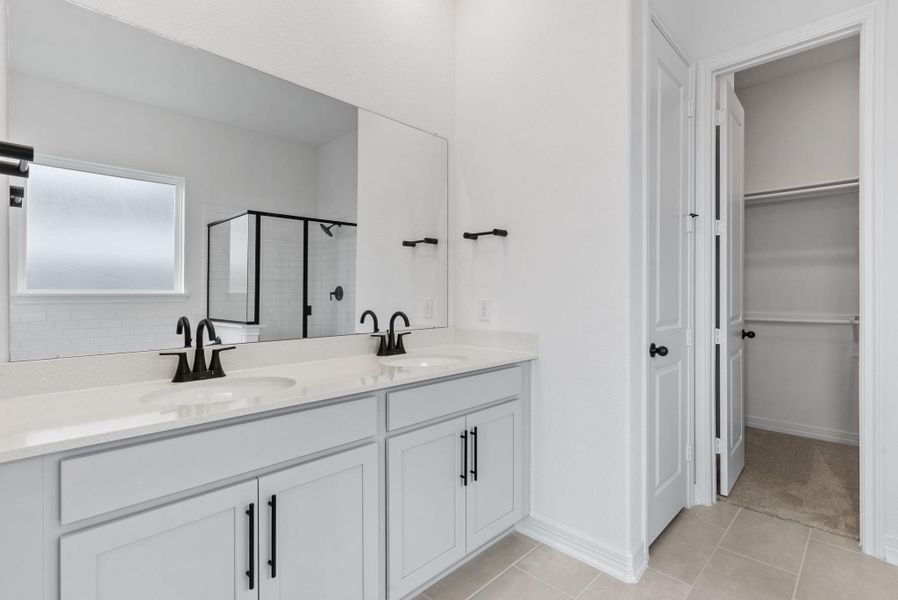 Primary bath featuring the AW Collection® Foundry with a dual-sink vanity, cream cabinetry, vintage-inspired finishes, and matte black accents for a refined, city-inspired vibe.”