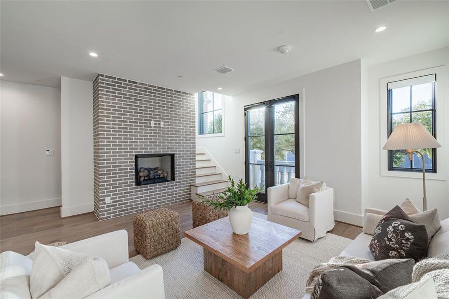 Living room with a brick fireplace, a healthy amount of sunlight, and light hardwood / wood-style floors