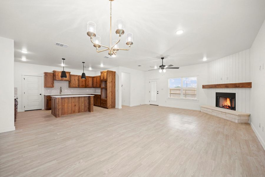 A combined living space features a cozy fireplace and a functional kitchen island, all set on light wood flooring.