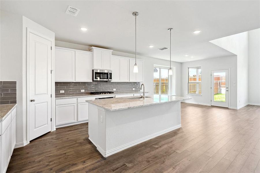 Kitchen featuring white cabinetry, tasteful backsplash, sink, light stone countertops, and dark hardwood / wood-style floors