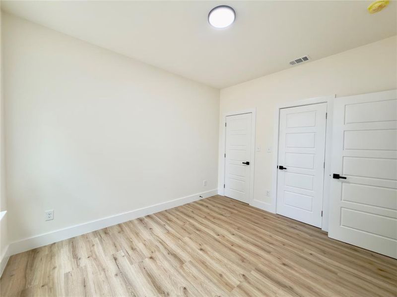Room featuring light-toned wood-finish flooring, white baseboards, and neutral wall paint