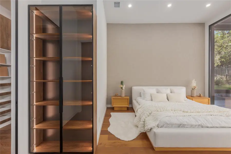 Hardwood floors and generous natural illumination complement this serene, light-filled sleeping space.