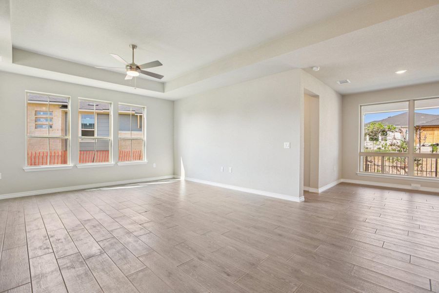 Unfurnished room featuring light wood-style floors, a ceiling fan, and a tray ceiling