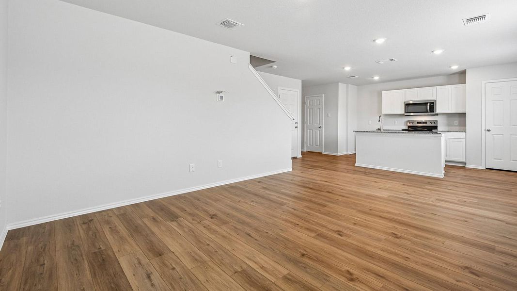 An open-concept living space with lustrous wood flooring flows seamlessly into a modern kitchen.