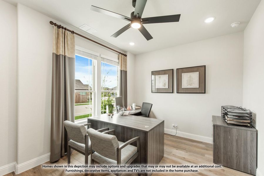 Home office with L-shaped desk, ceiling fan, hardwood floors, and large window with gray curtains