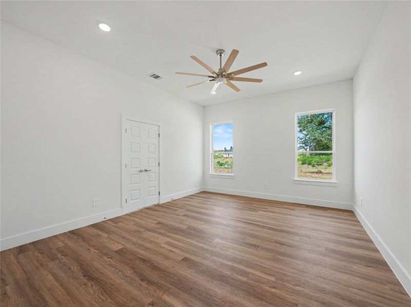 Expansive room featuring wood-finish flooring, crisp white walls, and a contemporary ceiling fan
