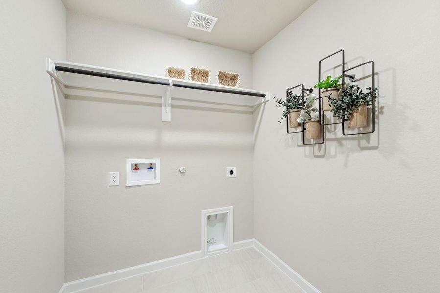 Laundry room with hanging rod, shelf, washer and dryer hookups, and wall-mounted plant decor Laundry room with hanging rod, shelf, washer and dryer hookups, and wall-mounted plant decor