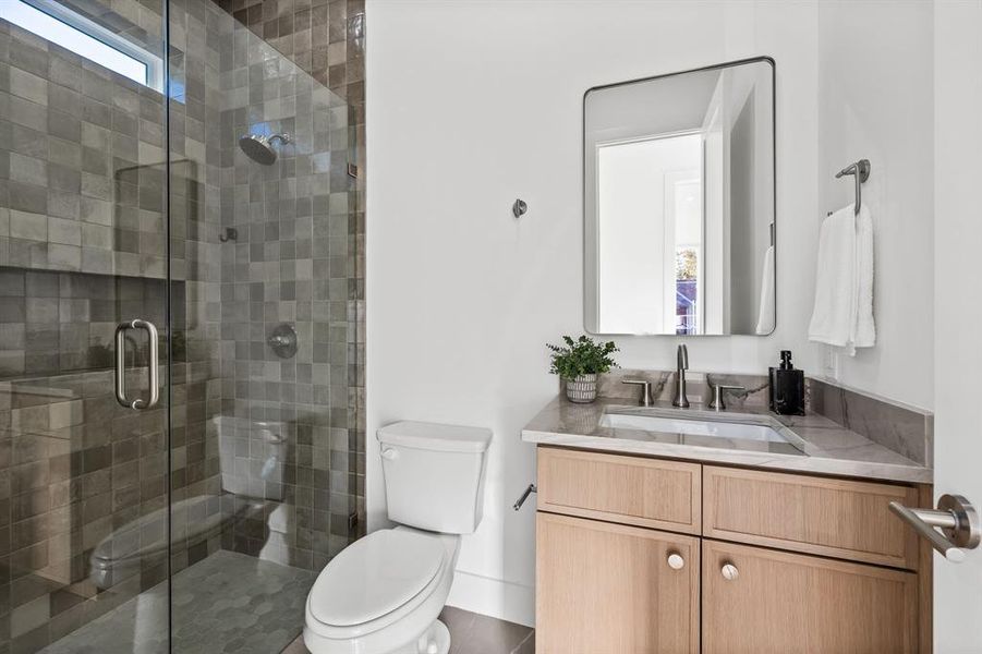 Bathroom featuring tile patterned floors, vanity, an enclosed shower, and toilet