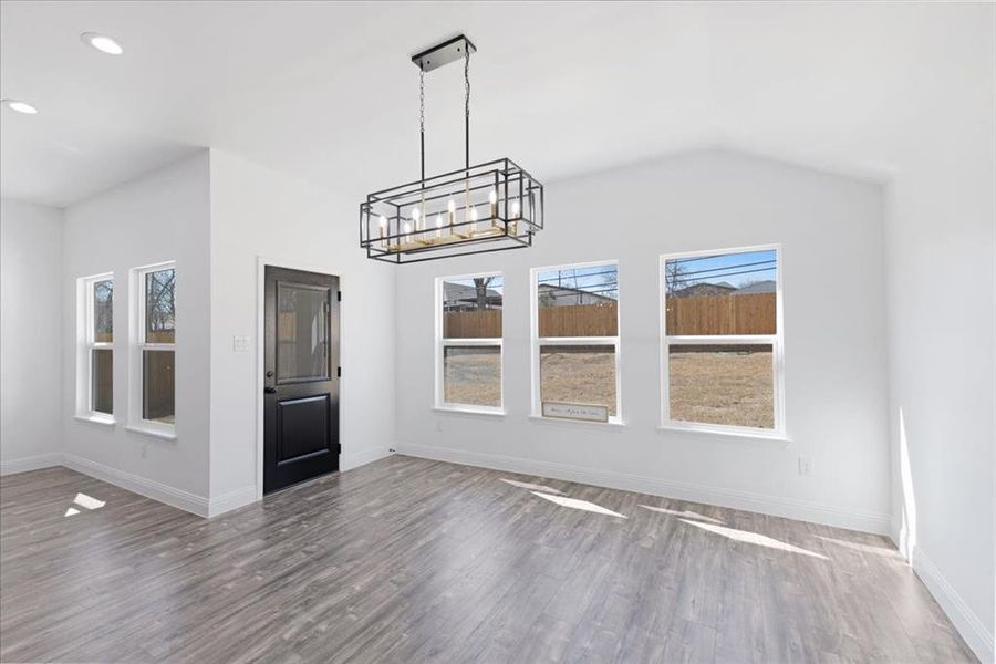 Unfurnished dining area with a notable chandelier, baseboards, dark wood-type flooring, and recessed lighting