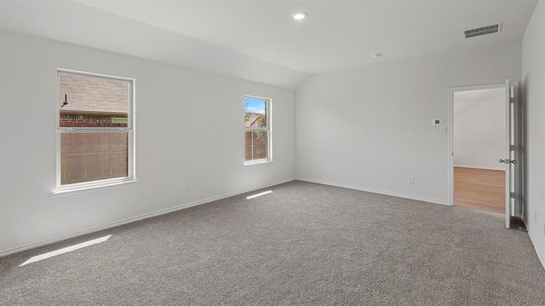 Spacious room featuring neutral carpeting, white walls, two windows, recessed lighting, and a white paneled door