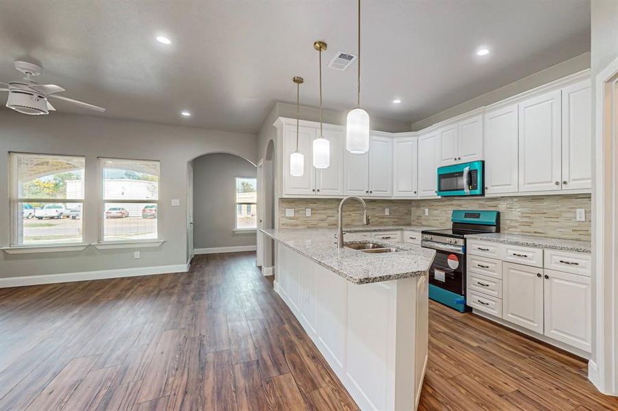 Kitchen featuring tasteful backsplash, dark wood-type flooring, stainless steel appliances, and sink