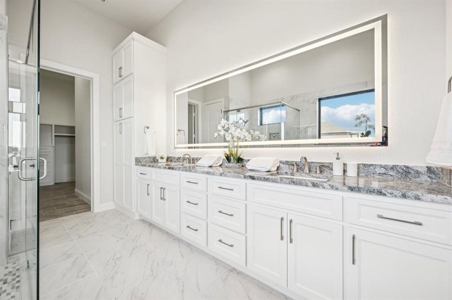 Primary ensuite bathroom with designer lighting, extra tall linen storage tower, fogless mirror, and connection to extra-large walk-in closet.