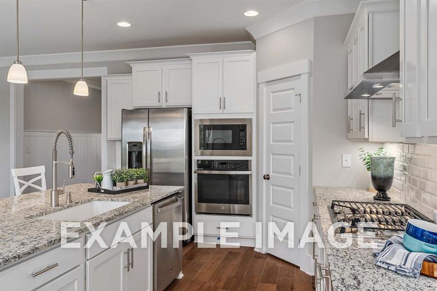 Kitchen with white cabinets, wall chimney exhaust hood, sink, and stainless steel appliances