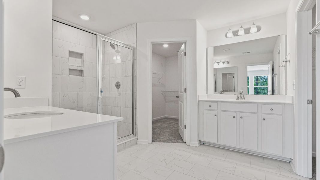 luxury owner's suite bath with dual vanities, water closet and tile shower