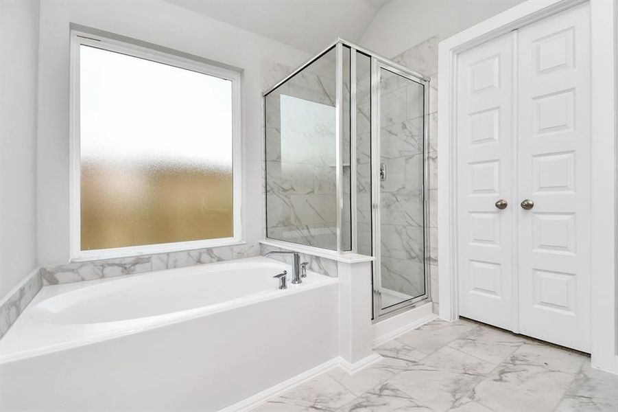 This additional view of the primary bath features a walk-in shower with the tile surround and separate garden tub perfect for soaking after a long day. Sample photo of similar plan. Actual colors and selections may vary.