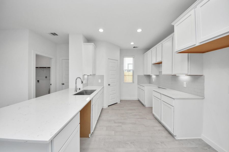 The kitchen is a culinary haven, featuring granite countertops, a tile backsplash, stainless steel appliances, 42” upper cabinets, and undercabinet lighting. Sample photo of completed home with similar floor plan. Actual colors and selections may vary.